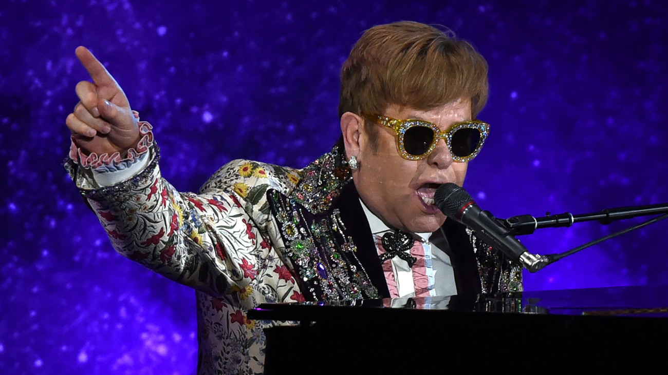 Elton John devant son piano en train de chanter sur scène